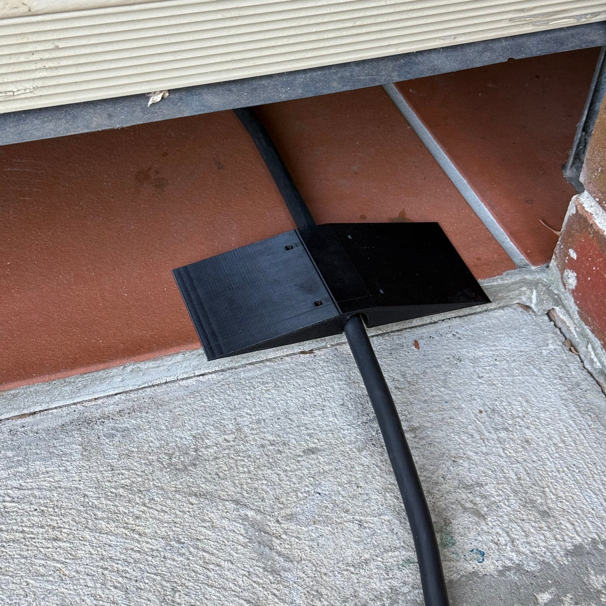 Center-wedge EV charging cable garage door pass-through protector
