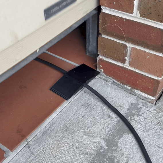 Center-wedge EV charging cable garage door pass-through protector