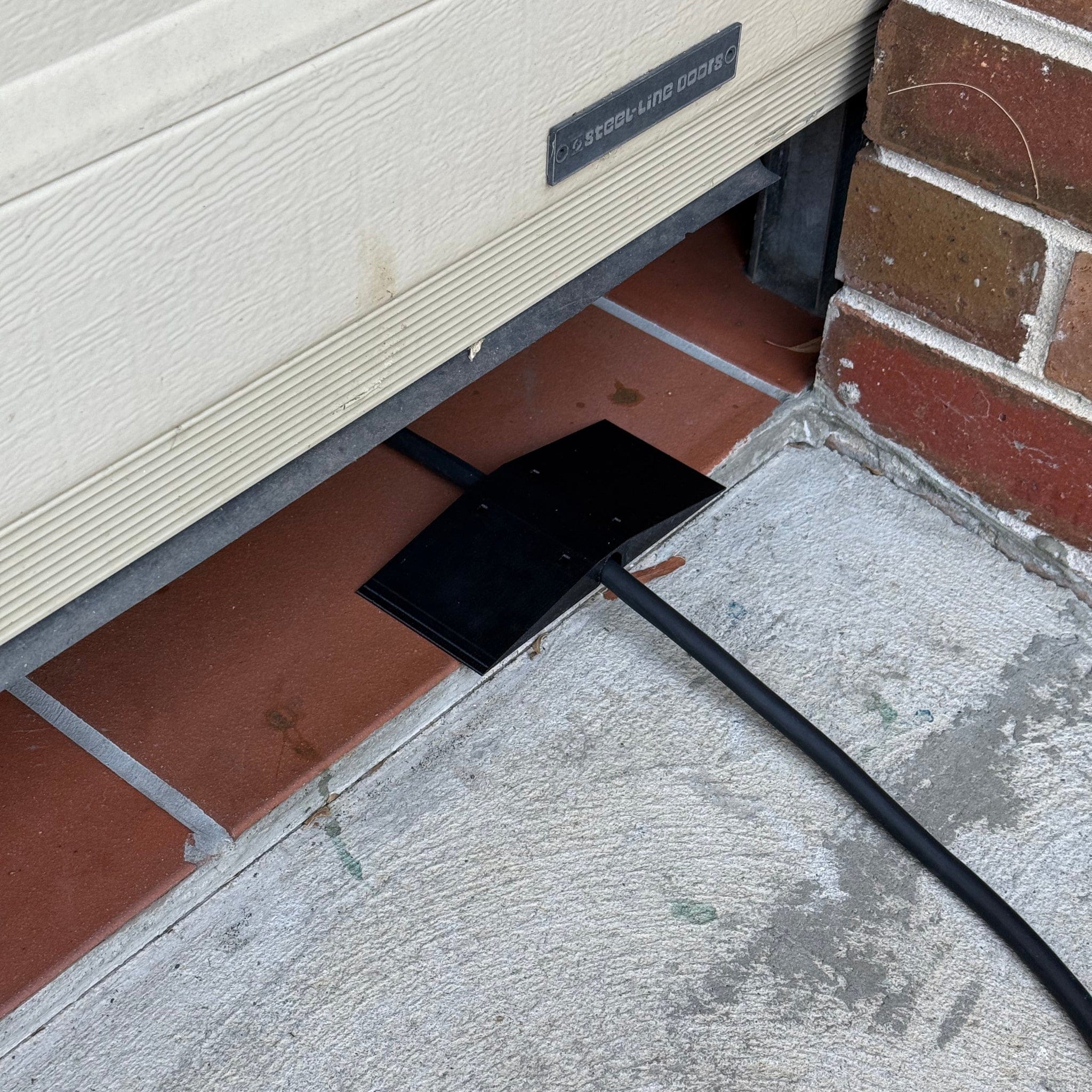 Center-wedge EV charging cable garage door pass-through protector